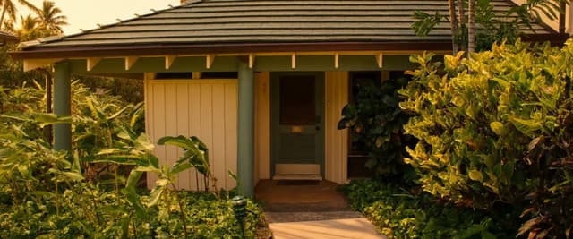 Beachfront villa with dark roof and tan walls surrounded by tropical plants, Poipu Beach, Kauai